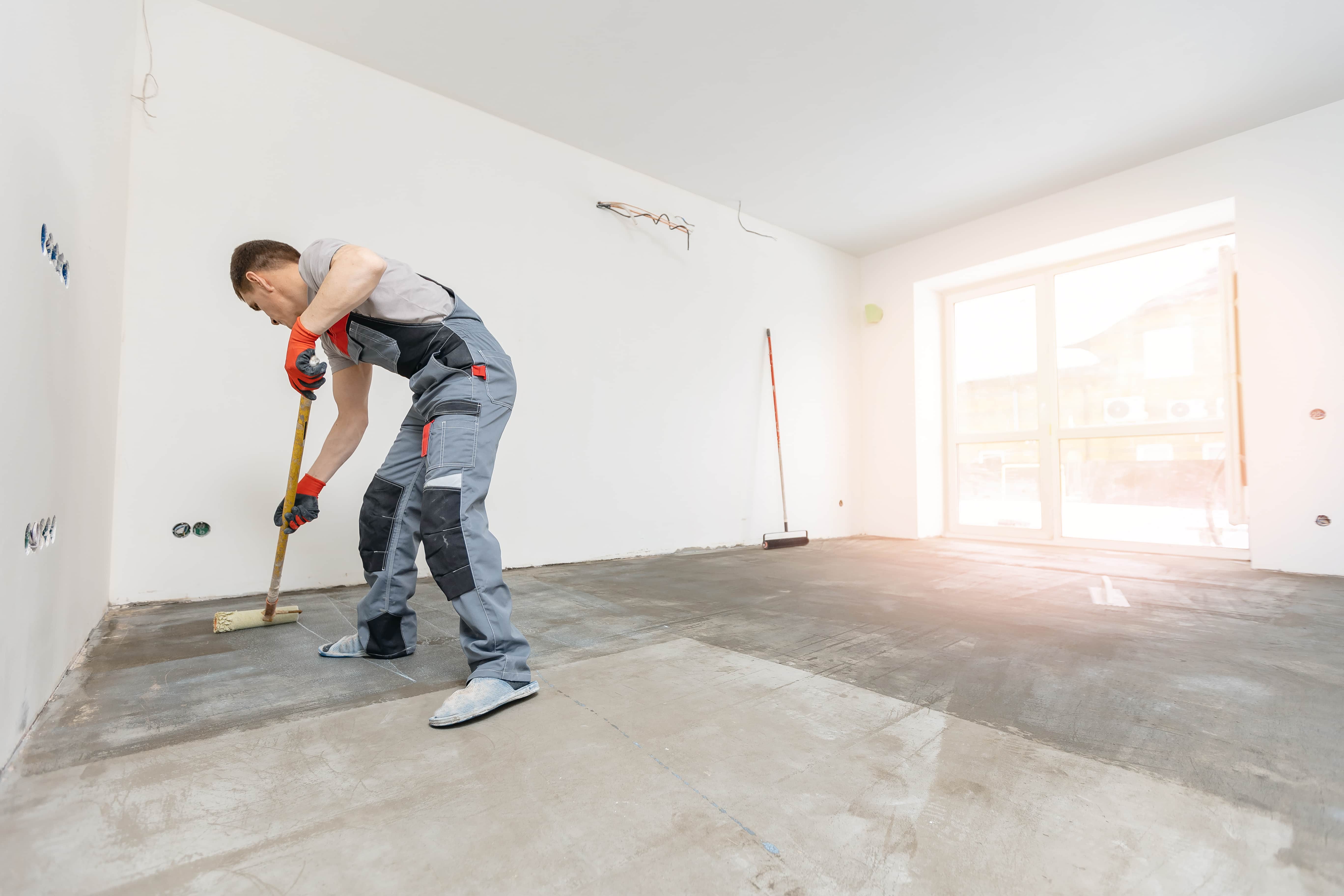 Bright residential room with primed concrete floor in progress